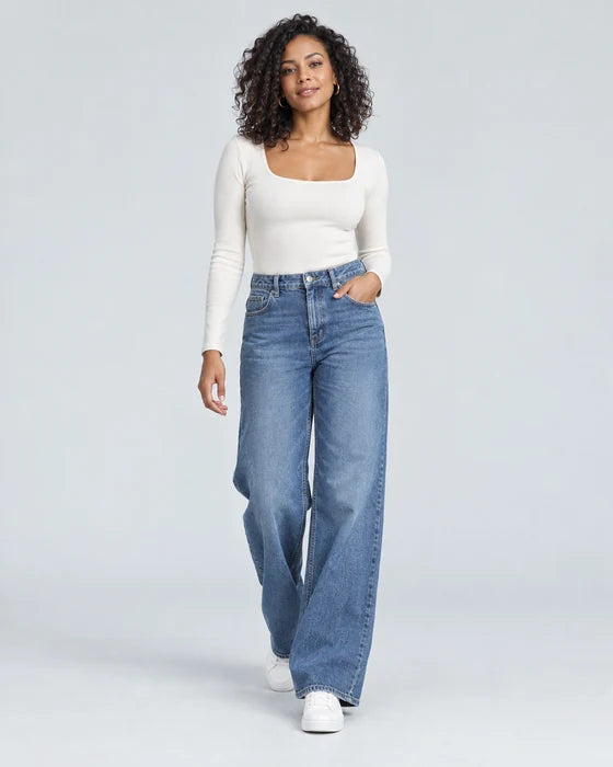 Model in an ivory top and wide-leg blue jeans